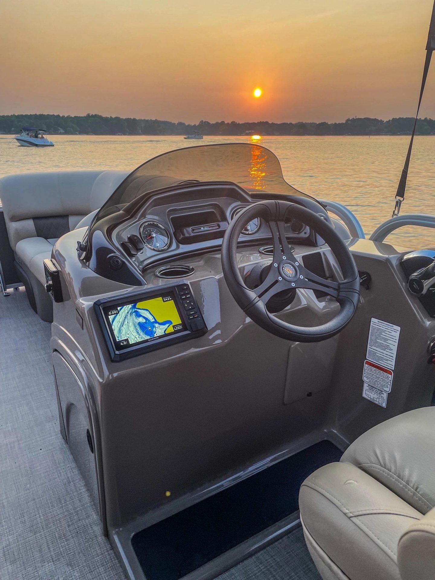 The pontoon helm and Garmin GPS with the sun setting over Lake Wylie